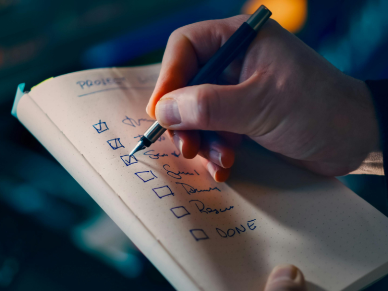Mano escribiendo una lista de tareas para decidir qué proceso automatizar primero