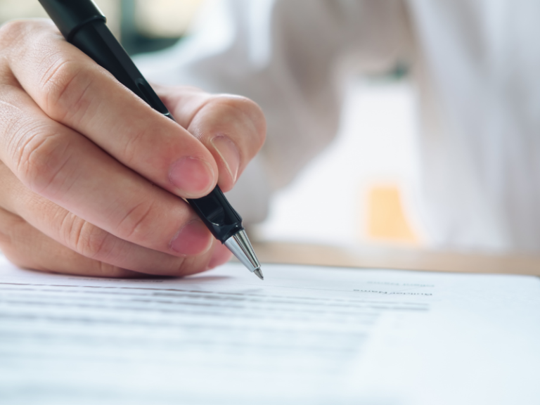 Firma de un contrato de outsourcing TI con pluma sobre el documento