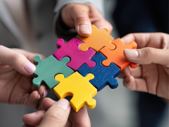 Manos colaborando para ensamblar piezas de puzzle de colores vibrantes, representando trabajo en equipo y colaboración en ecosistemas de innovación