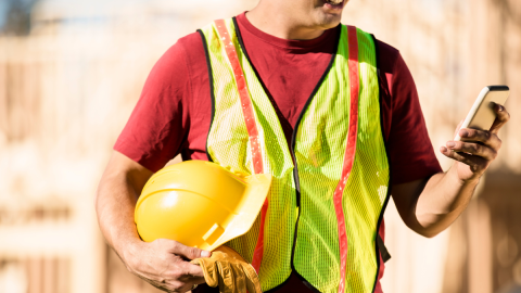 Trabajador en terreno utilizando teléfono móvil para gestión digital de seguridad operacional